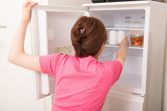 冷蔵庫の中を見ている女性の写真